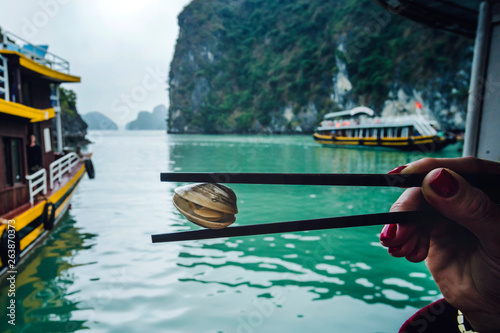 Vietnam green mussel with spicy seafood sauce on sticks in the hands of women. photo