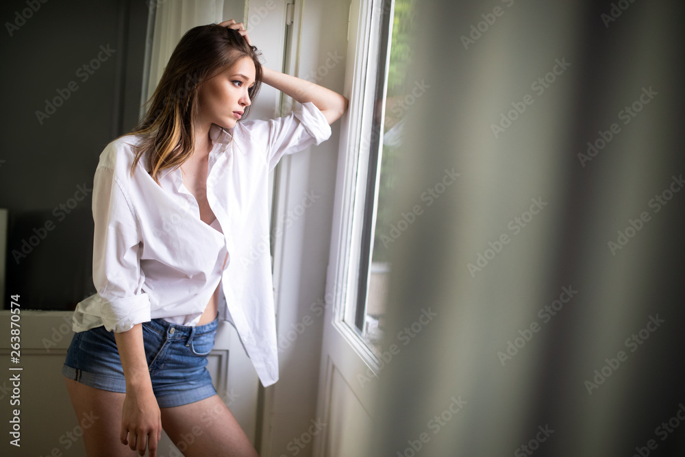 Portrait of sensual young woman with makeup posing by window