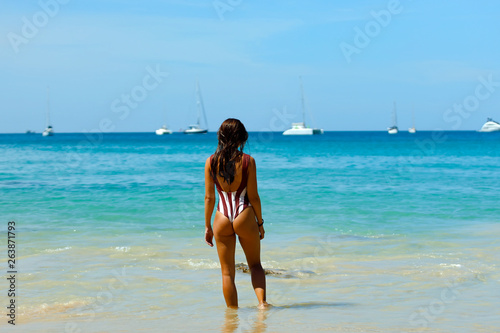 Girl looks at the ocean in a swimsuit