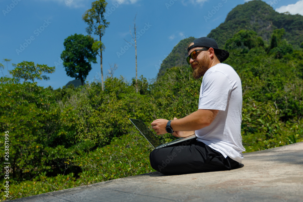 Obraz premium Young stylish bearded blogger working on vacation in the mountains.
