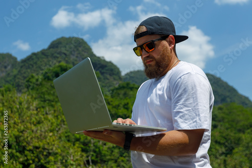 Young stylish bearded blogger working on vacation in the mountains.