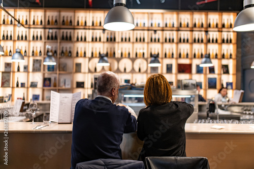 Coppia che degusta vino in taverna, pub, vineria, con bottiglie di rosso e bianco esposte ne l bar photo