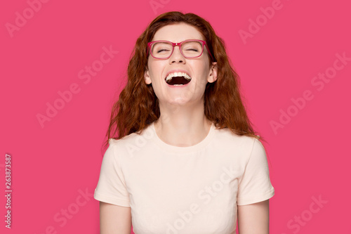 Fotografie Happy red-haired girl in glasses laughing at joke