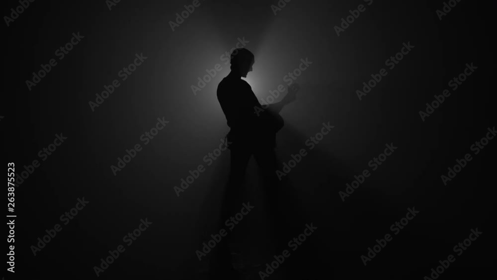 Silhouette of man playing acoustic guitar in dark Silhouette of man playing acoustic guitar in dark