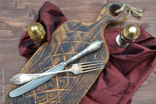 Aged cutting board with antique silver pepperbox and fork on wooden table.  Concept of healthy diet. photo