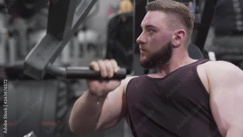 Confident bodybuilder training on a chest press with a single arm, close up shot Confident bodybuilder training on a chest press with a single arm, close up shot