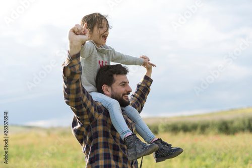 Father with little girl on his shoulder in outdoors spring image