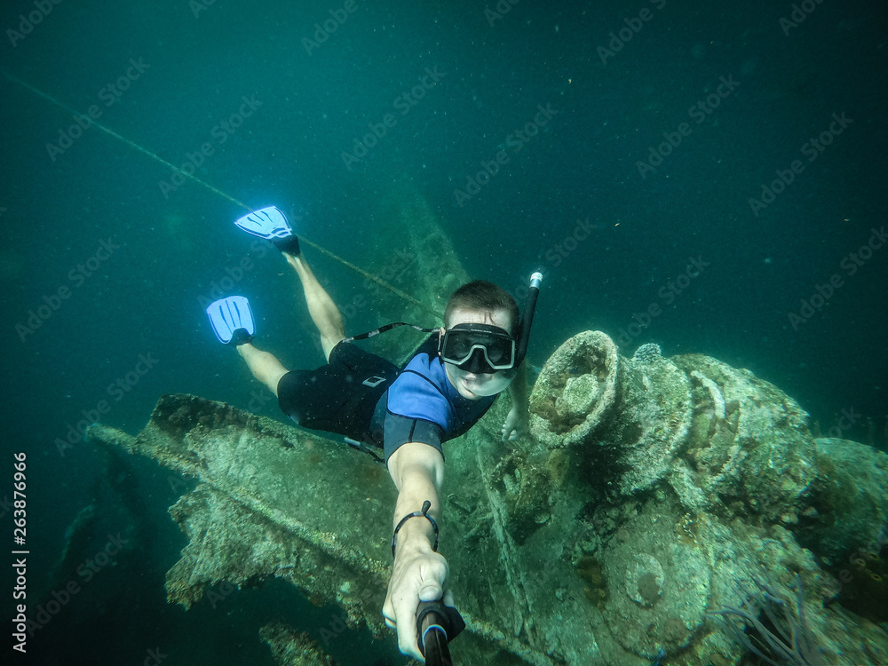Fototapeta premium Free diver taking selfie with sunken ship on background