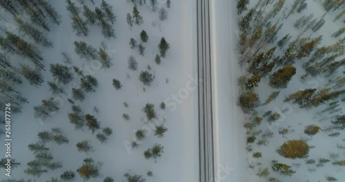 Aerial, tilt up, drone shot, above a road between Sarkijarvi lake and Sarkitunturi, in arctic wilderness, in Pallas-yllastunturi national park, on a sunny, winter day, in Muonio, Lapland, Finland photo