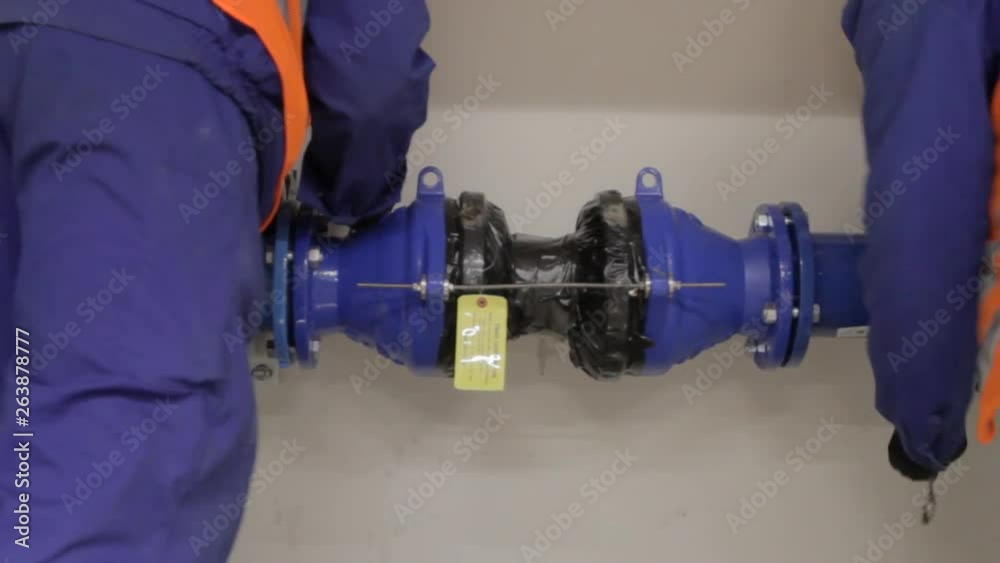 Two workers connect a hydraulic pipe connector between two pipes. Tracking shot. Two workers connect a hydraulic pipe connector between two pipes. Tracking shot.