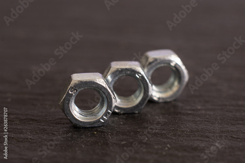 Closeup of three whole metal locking nuts work item on grey stone
