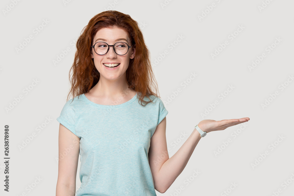 Smiling redhead girl in glasses show blank copy space Smiling redhead girl in glasses show blank copy space