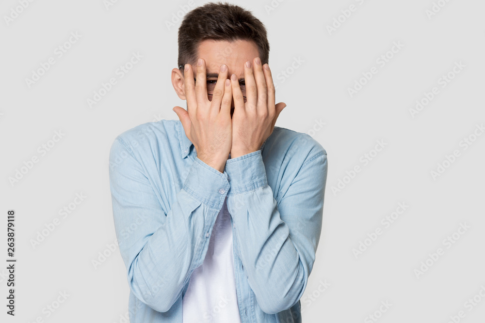 Caucasian man isolated on grey background peek through fingers Caucasian man isolated on grey background peek through fingers