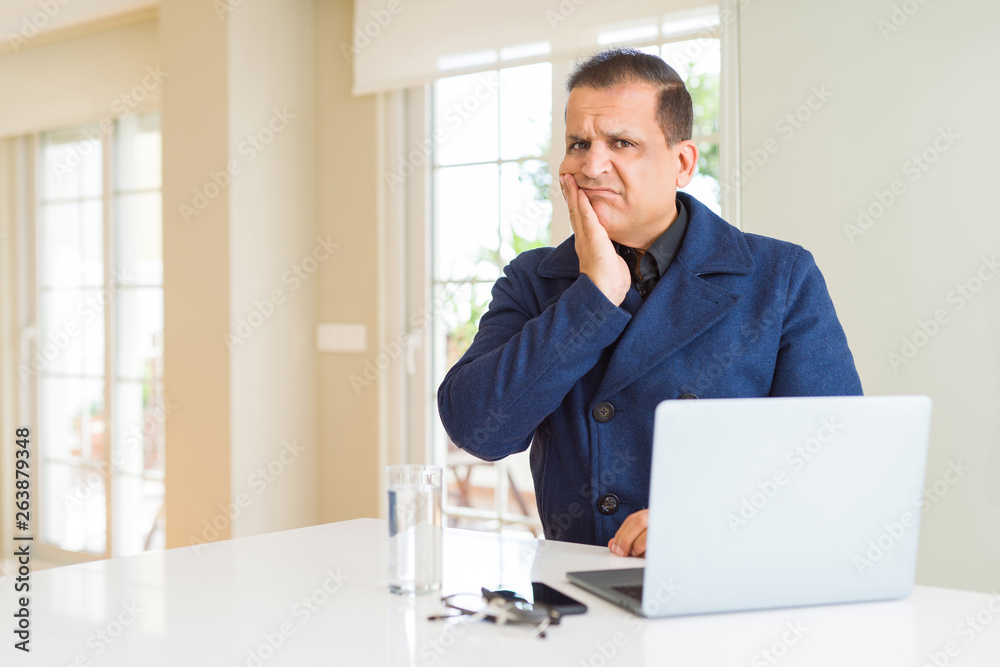 Middle age business man working using laptop thinking looking tired and bored with depression problems with crossed arms.