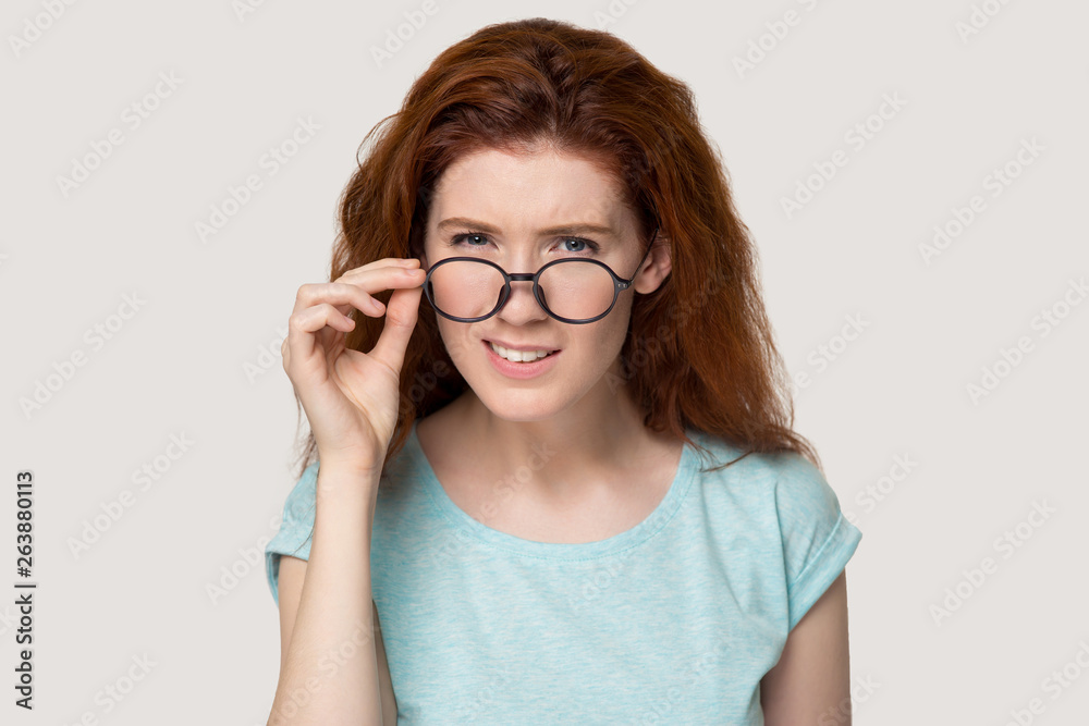 Doubtful red-haired girl take off glasses feeling hesitant