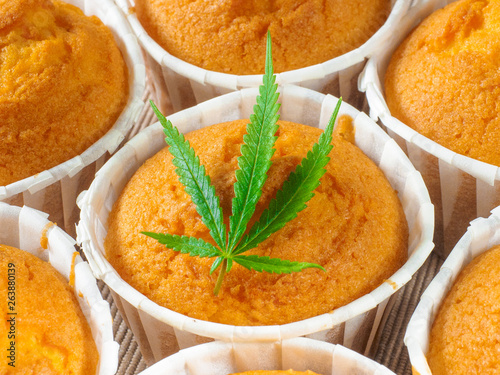 Freshly baked cinnamon mini muffins with cannabis and buds of marijuana on the table. Concept of cooking with cannabis herb. Treatment of medical marijuana for use in food.