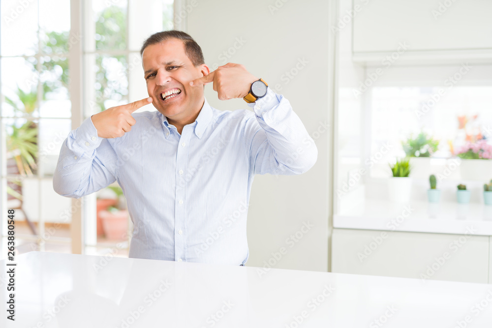 Middle age man sitting at home smiling confident showing and pointing with fingers teeth and mouth. Health concept.