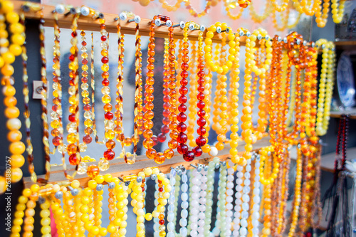 The set of an orange Amber beads hangs on a show-window of street shop