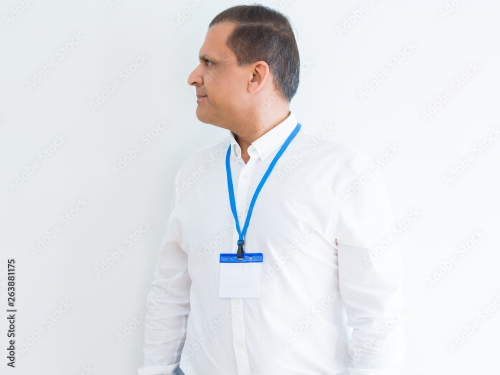 Middle age business man wearing ID card over white background looking to side, relax profile pose with natural face with confident smile. Middle age business man wearing ID card over white background looking to side, relax profile pose with natural face with confident smile.