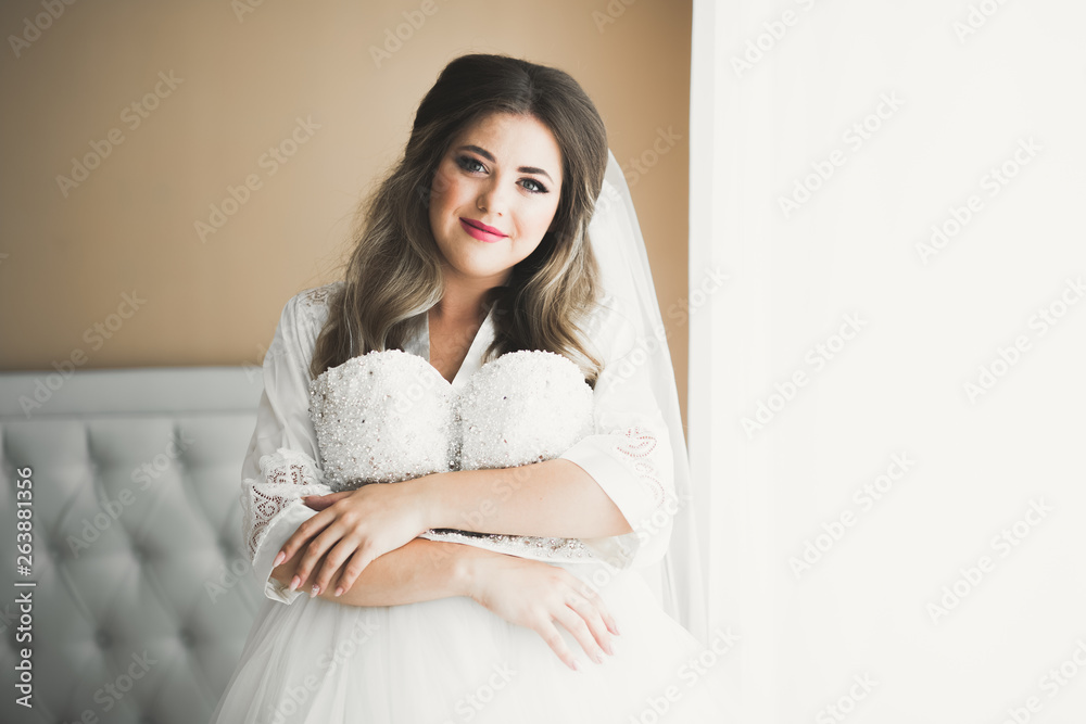 Gorgeous bride in robe posing and preparing for the wedding ceremony face in a room Gorgeous bride in robe posing and preparing for the wedding ceremony face in a room