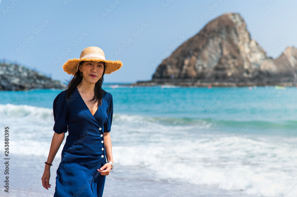 Fashionable Asian girl walking on the beach