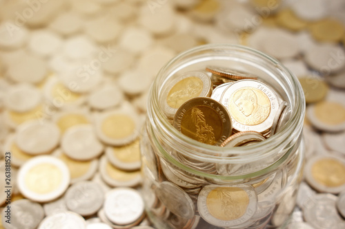 Close-up image of a glass jar full of new Thai baht coins. Business and finance concept.