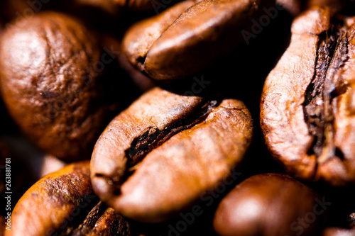 Macro close up of pile of roasted brown coffee beans in natural sunlight showing details of surface