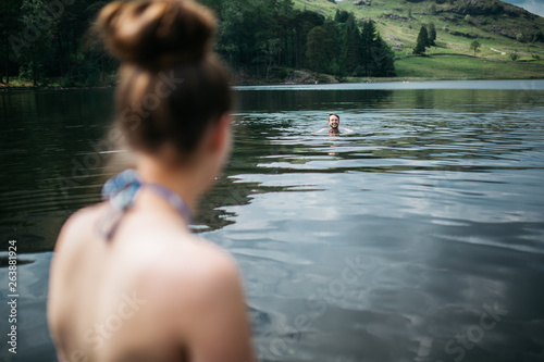 Fototapeta Naklejka Na Ścianę i Meble -  Man swimming far away as woman looks on