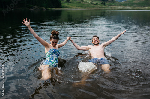 Couple jumping into water with joy
