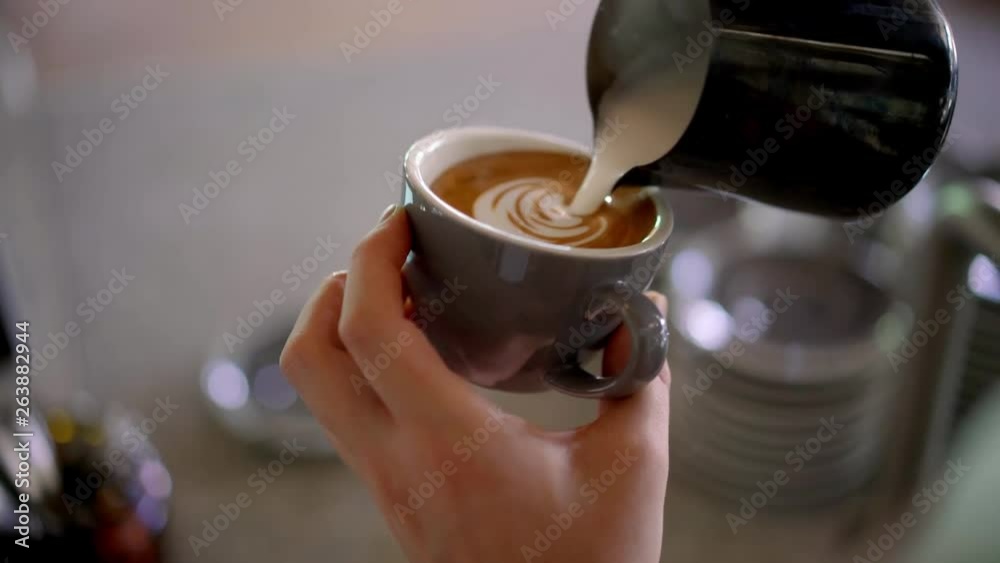 Barista pouring milk in coffee doing latte art