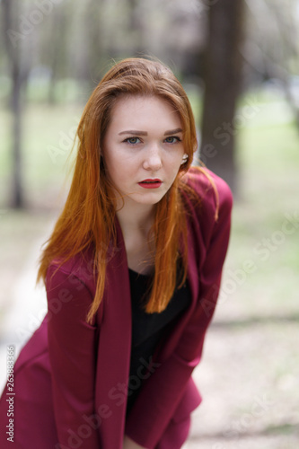 Red-haired slender girl in the Park among the trees