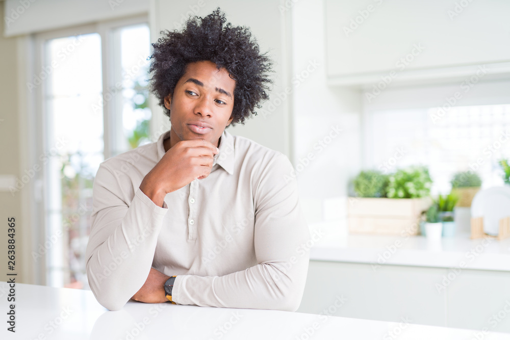 African American man at home looking confident at the camera with smile with crossed arms and hand raised on chin. Thinking positive. African American man at home looking confident at the camera with smile with crossed arms and hand raised on chin. Thinking positive.