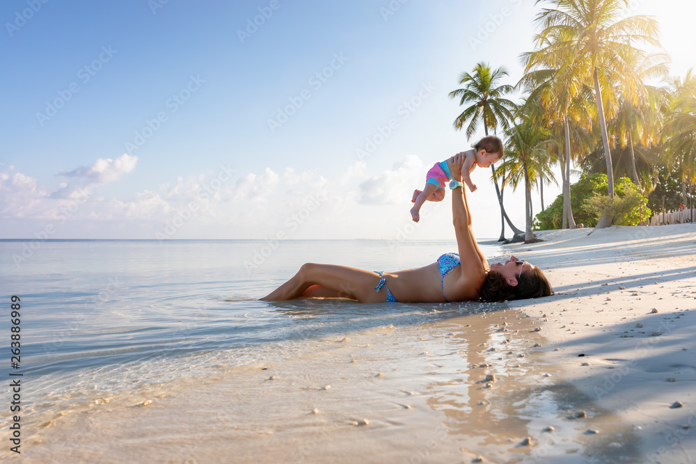 Obraz premium Mutter und Baby liegen am tropischen Strand und genießen ihren Familien Urlaub