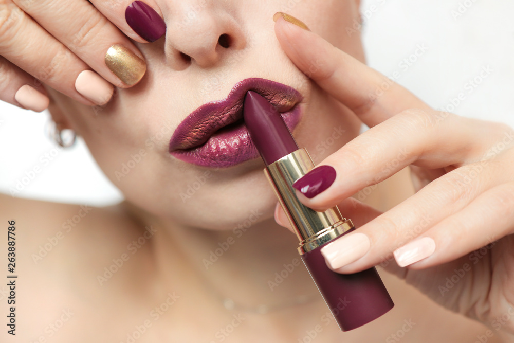 Obraz premium Multi-colored nail design.Trendy Burgundy nail Polish and lip makeup.Glamorous plum Burgundy lipstick.