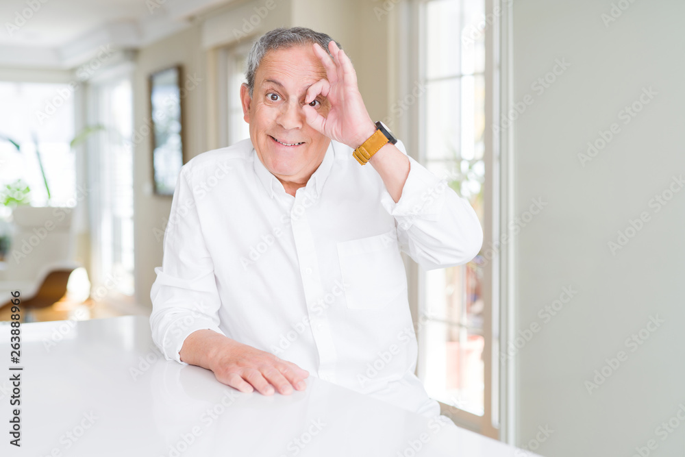 Handsome senior man at home doing ok gesture with hand smiling, eye looking through fingers with happy face. Handsome senior man at home doing ok gesture with hand smiling, eye looking through fingers with happy face.