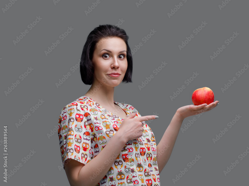 European woman doctor holds an apple in hand. photo session on a gray background in the photo studio. The average plan. Portrait. Doctor nutritionist. European woman doctor holds an apple in hand. photo session on a gray background in the photo studio. The average plan. Portrait. Doctor nutritionist.
