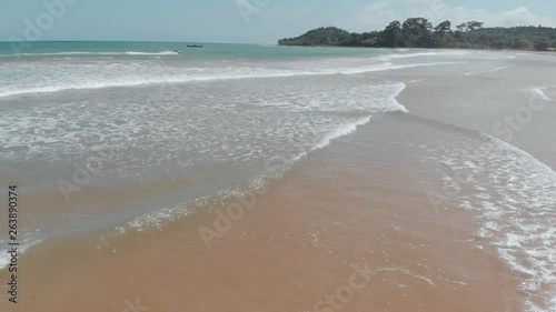 A beautiful drone shot taken at a beach in Ghana, Africa on the western coast. There is a beautiful white sand beach and blue water with some jet skiing happening on a beautiful day at Busua Beach. photo