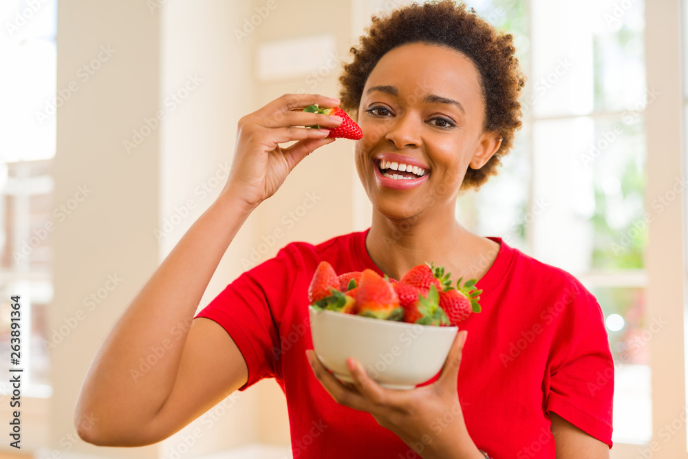 Beautiful young african woman with afro hair eating fresh strawberries Beautiful young african woman with afro hair eating fresh strawberries