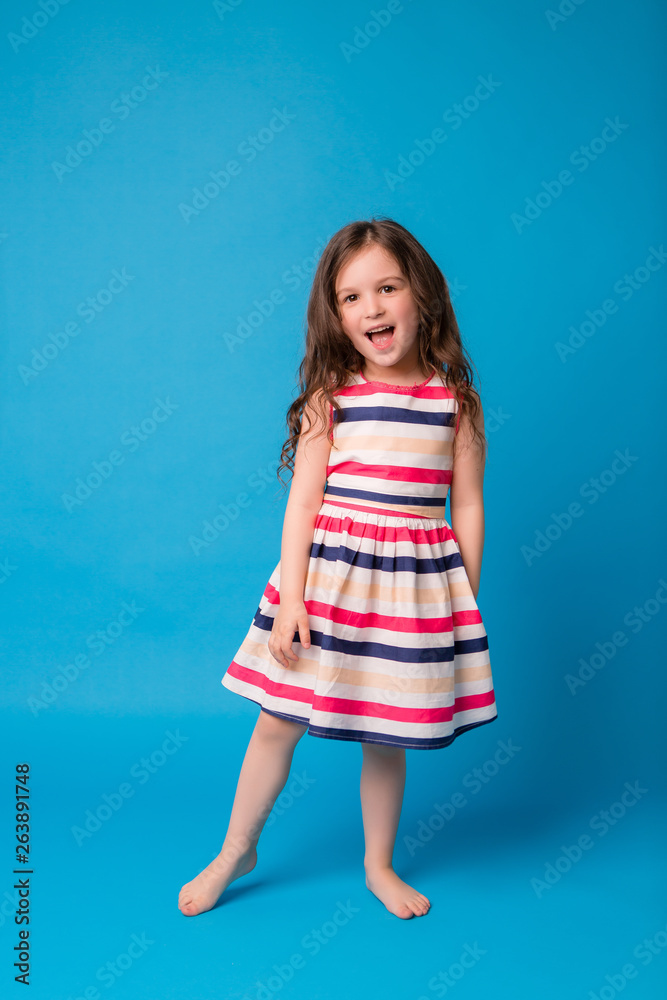 baby girl brunette in colorful dress smiling, isolate on blue background, children's emotions,Close-up portrait of dark-haired little girl smiling on isolated background baby girl brunette in colorful dress smiling, isolate on blue background, children's emotions,Close-up portrait of dark-haired little girl smiling on isolated background