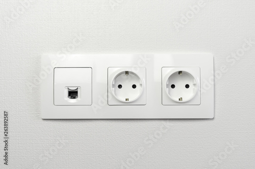 Electrical sockets on the wall with black connection internet plug and white wire. Socket set with usb cord and electricity cable with selective focus on neutral background.