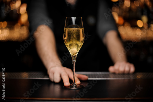 Close shot of glass with sparkling wine in the bartender's hands photo