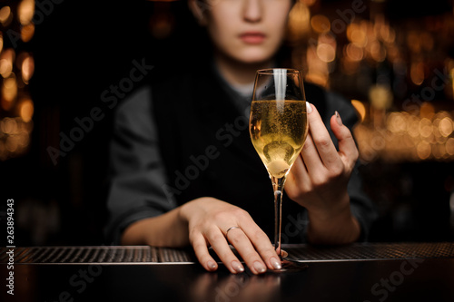 Close shot of glass full of sparkling wine in bartender's hands