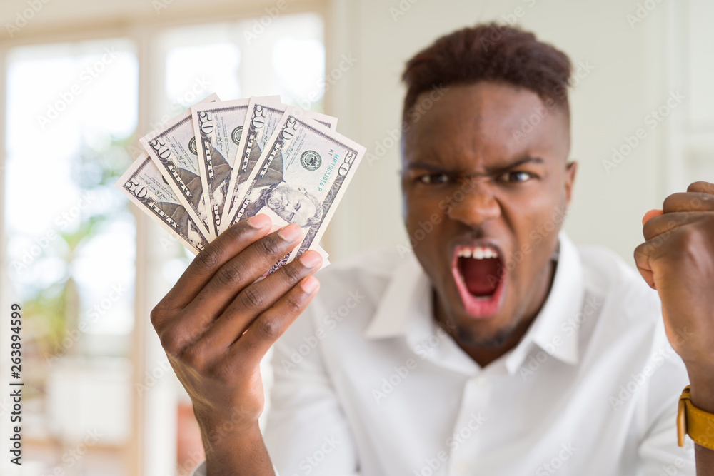 African american man holding fifty dollars bank notes annoyed and frustrated shouting with anger, crazy and yelling with raised hand, anger concept African american man holding fifty dollars bank notes annoyed and frustrated shouting with anger, crazy and yelling with raised hand, anger concept