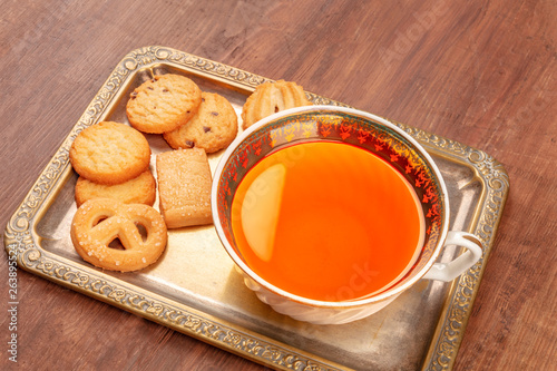 Danish butter cookies on a vintage tray with a cup of tea on a dark rustic wooden background with a place for text photo