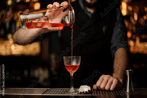 Canvas Print Bartender pours an alcohol cocktail using jar with sieve