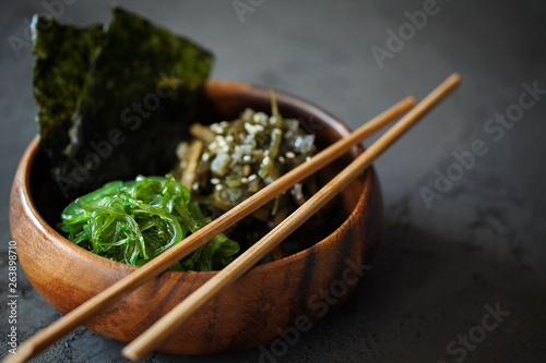 Traditional Japanese Snack - Chuka Wakame seaweed salad and crispy roasted nori sheets in wooden bowl on dark background with copy space for text.Healthy seafood high in vitamins