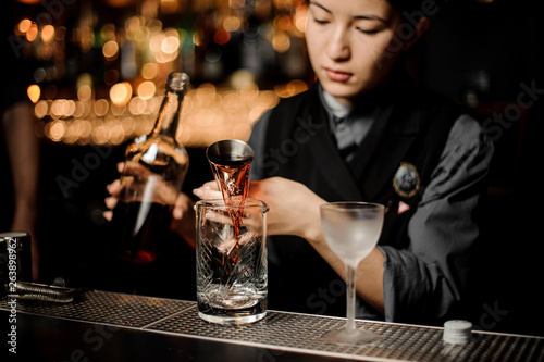 Bartender pouring an alcohol cocktail with jigger