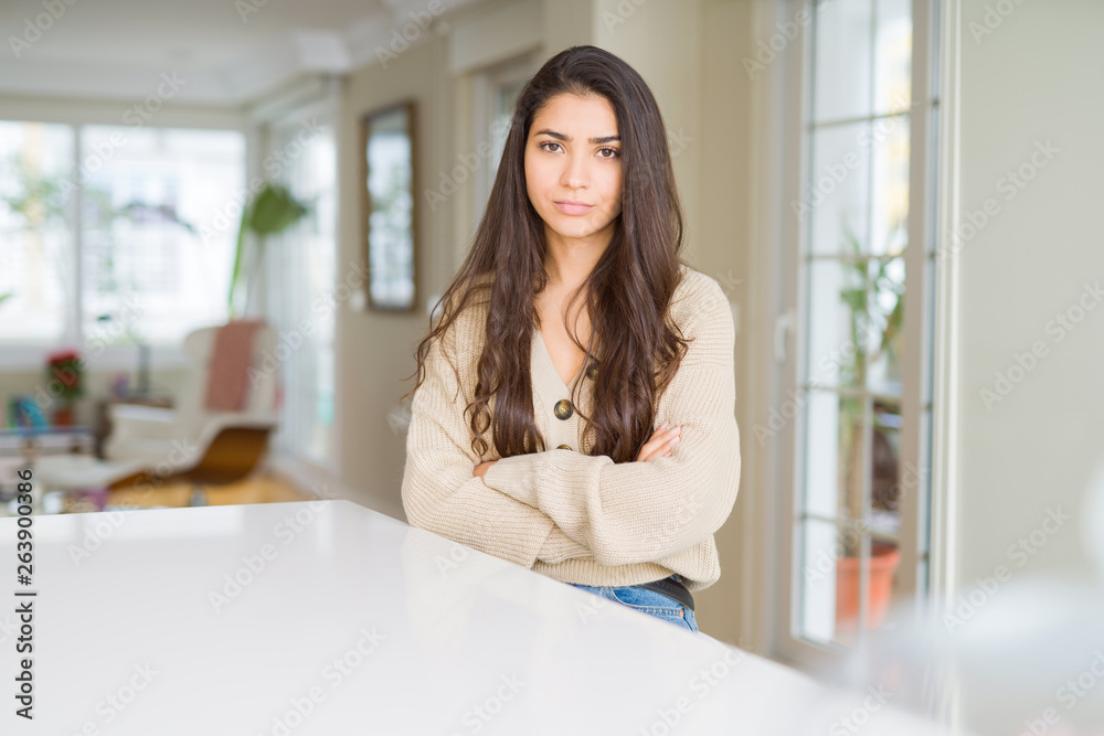 Young beautiful woman at home skeptic and nervous, disapproving expression on face with crossed arms. Negative person.