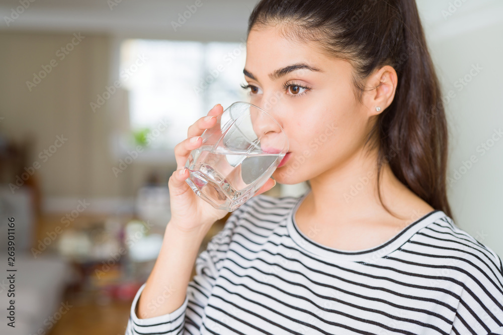 Beautiful young woman drinking a fresh glass of water at home Beautiful young woman drinking a fresh glass of water at home