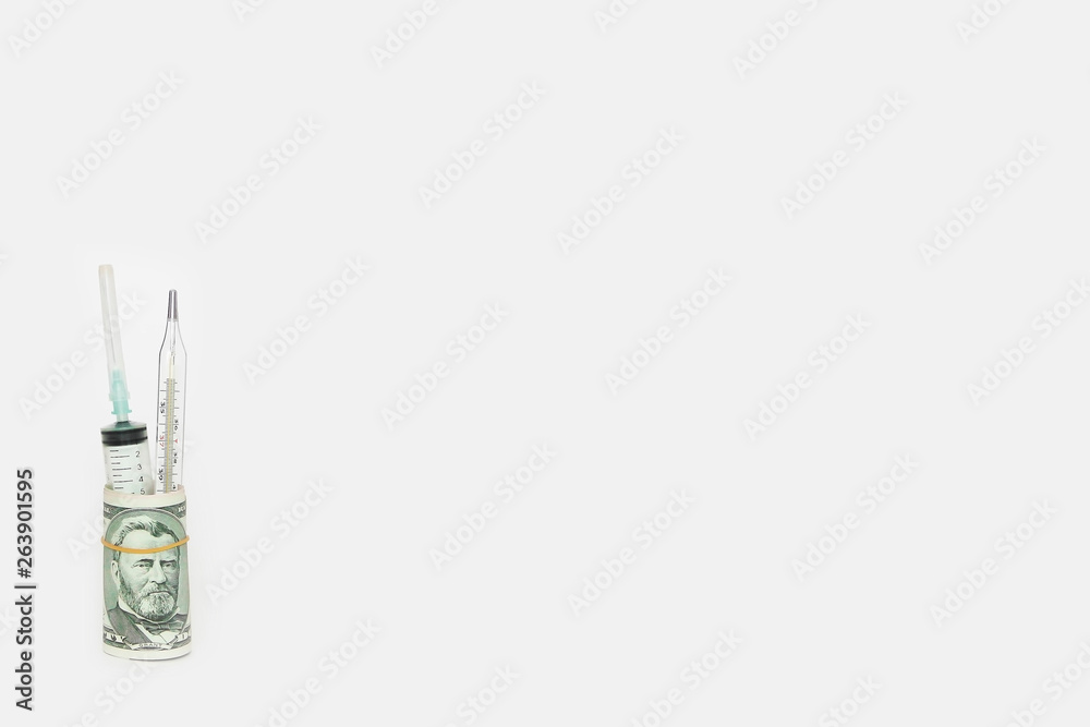 medical syringe and thermometer in a roll of dollars on a white background